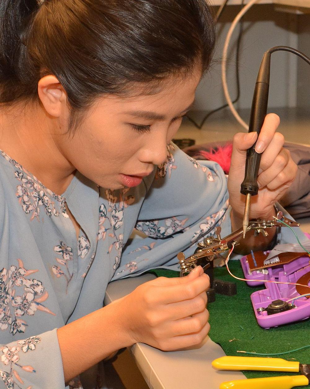 女学生在塑料玩具上焊接电线. 